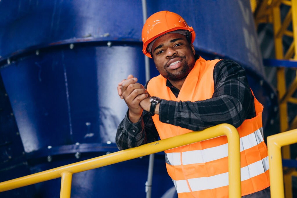 African american worker standing in uniform wearing a safety hat in a factory